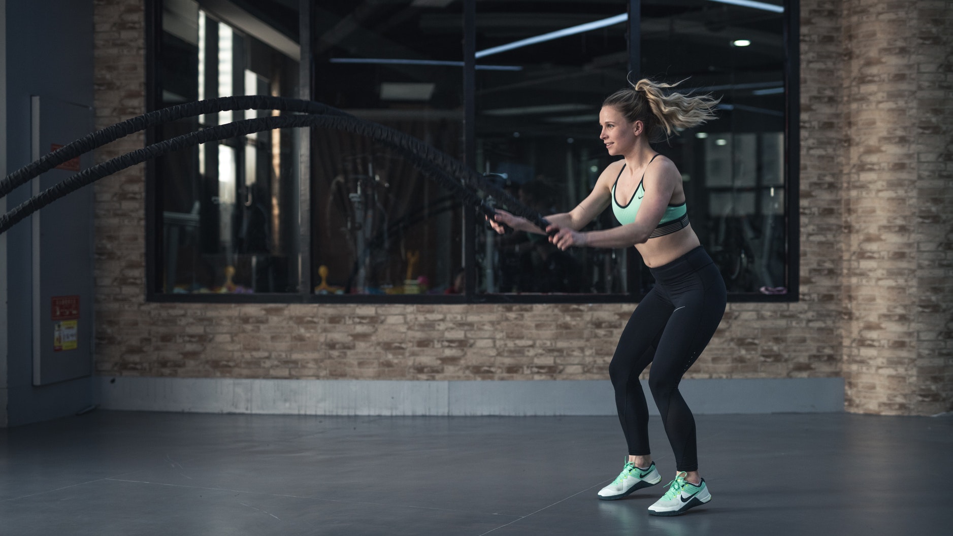 woman exercising two battle ropes