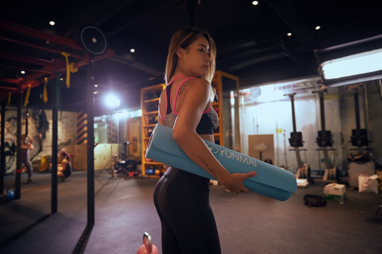 woman holding yoga mat in gym
