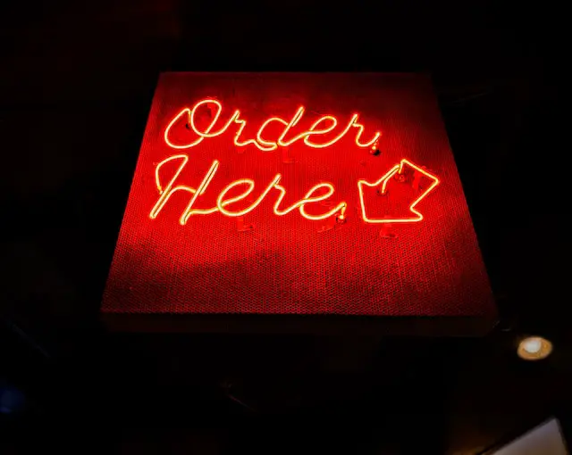 A red neon sign that says “order here”.