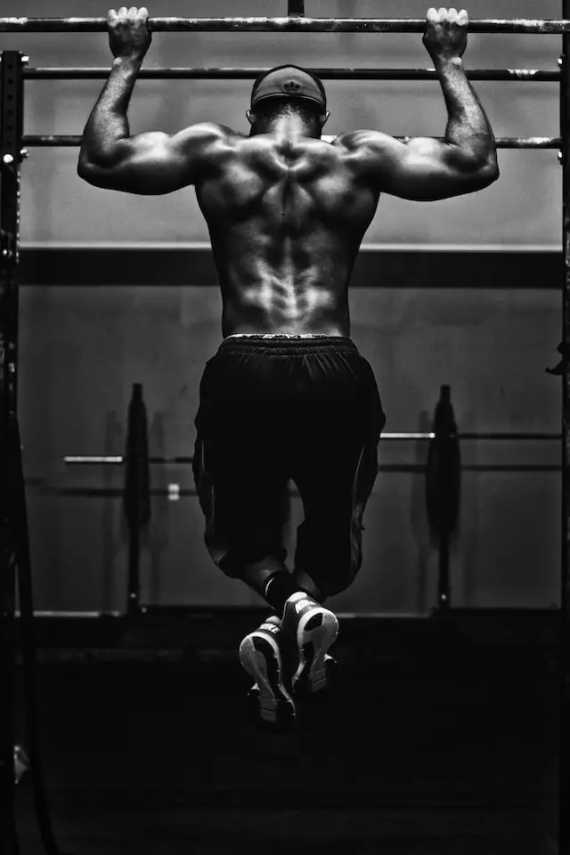 Photo from behind of a man doing pull-ups.