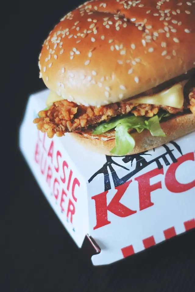 Fried chicken sandwich on top of KFC cardboard sandwich container.