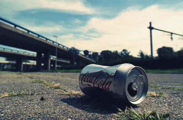 A picture of a crushed Coca-Cola can on the ground.