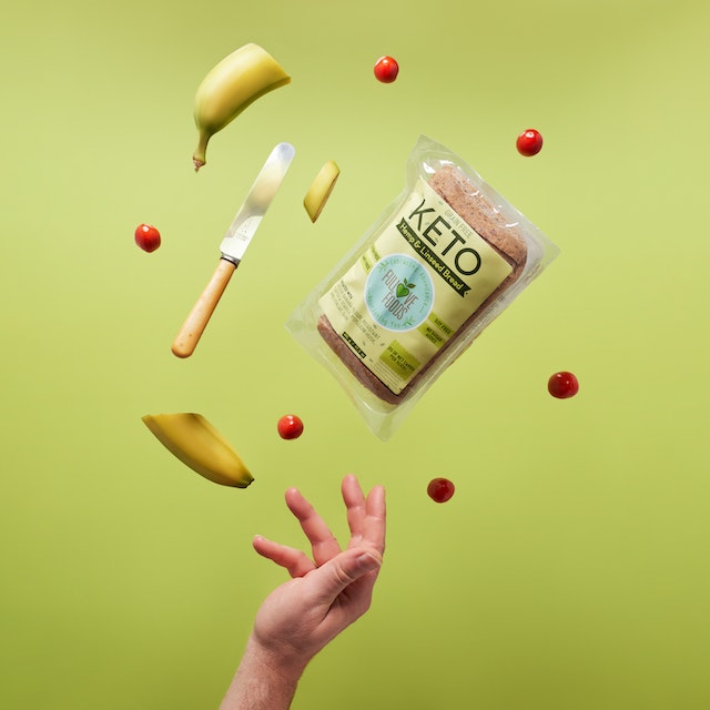 A hand catching a pack of bananas and keto bread through the air.