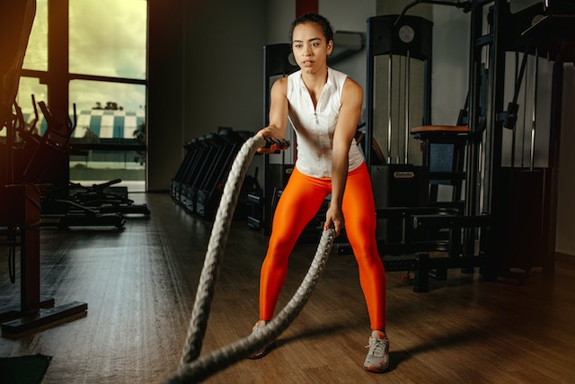 A woman working out with two ropes in a gym.