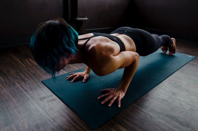 A woman planking on a fitness mat at home. 