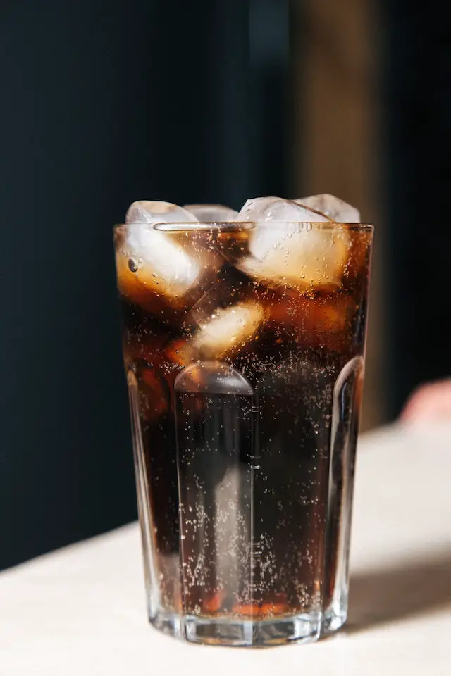 Wet drinking glass with diet coca cola and ice cubes.