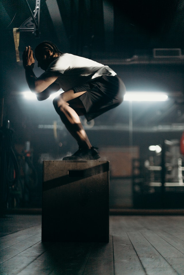 A man doing box jumps in a gym.