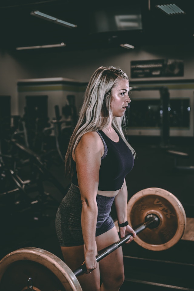 A woman lifting a barbell in the gym.