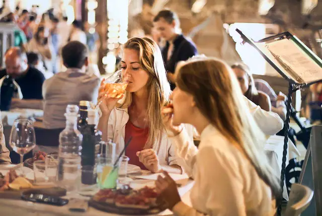 Two women enjoying their wine and food at a restaurant.