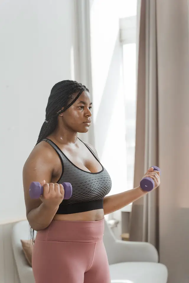 Braided-hair woman exercising using 2 small dumbbells.