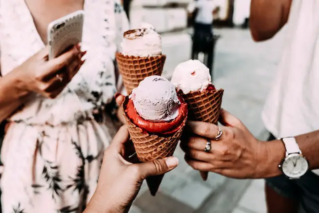 A group of friends clinking their ice creamson brown cone.