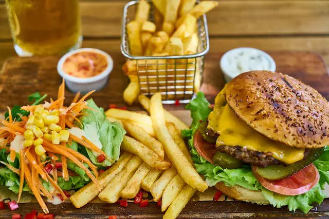 A table comprising a cheeseburger, fries and veggies