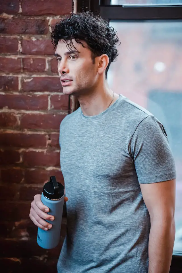 A man wearing sports attire holding a water bottle