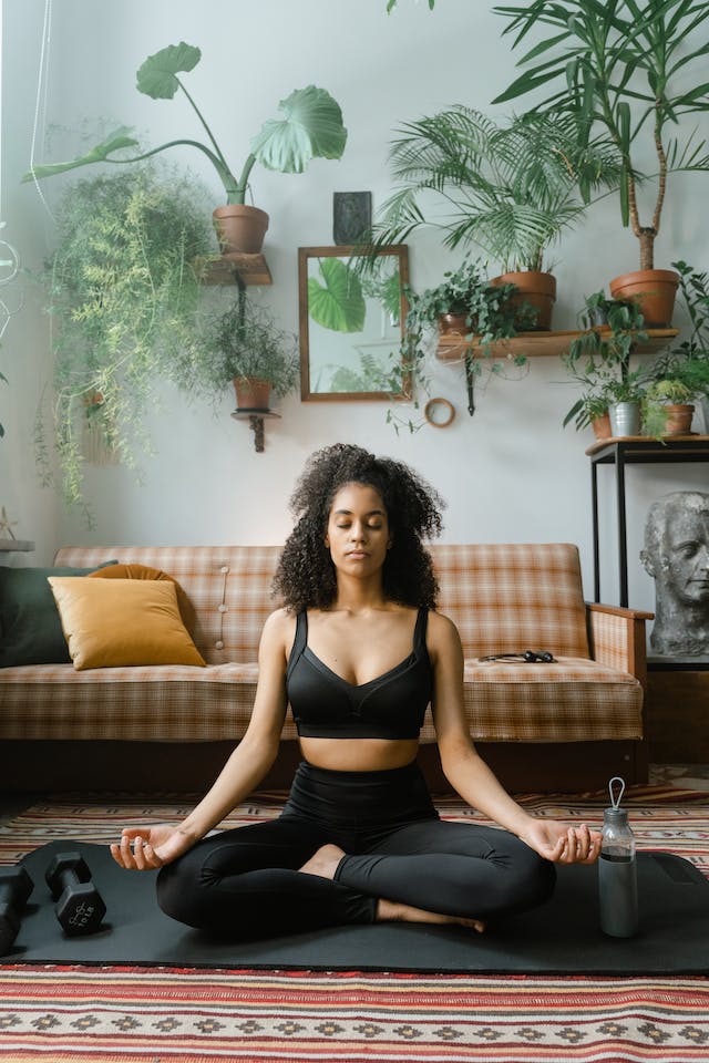 A woman meditating on a yoga mat with a bottle of water beside her