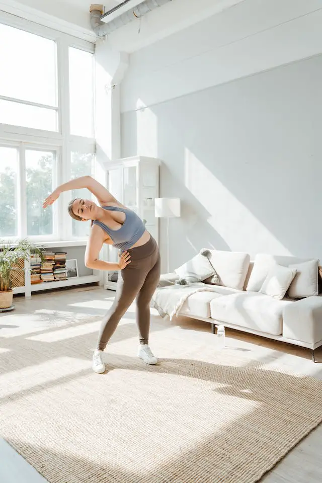 A woman in sports wear doing stretching exercises at home.