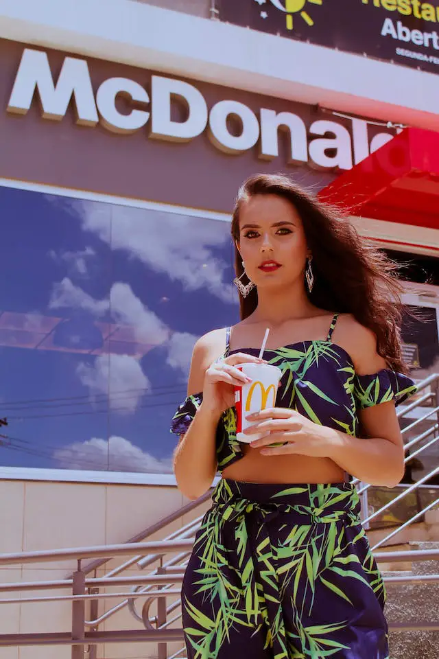 A woman standing outside McDonalds with a cup in her hand