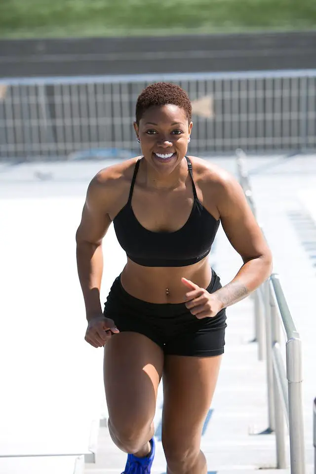 A woman jogging in a black sports bra and shorts smiling