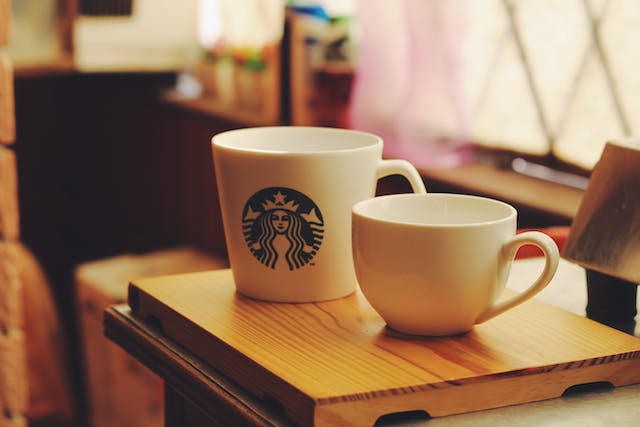 Two white ceramic Starbucks cups on a wooden board