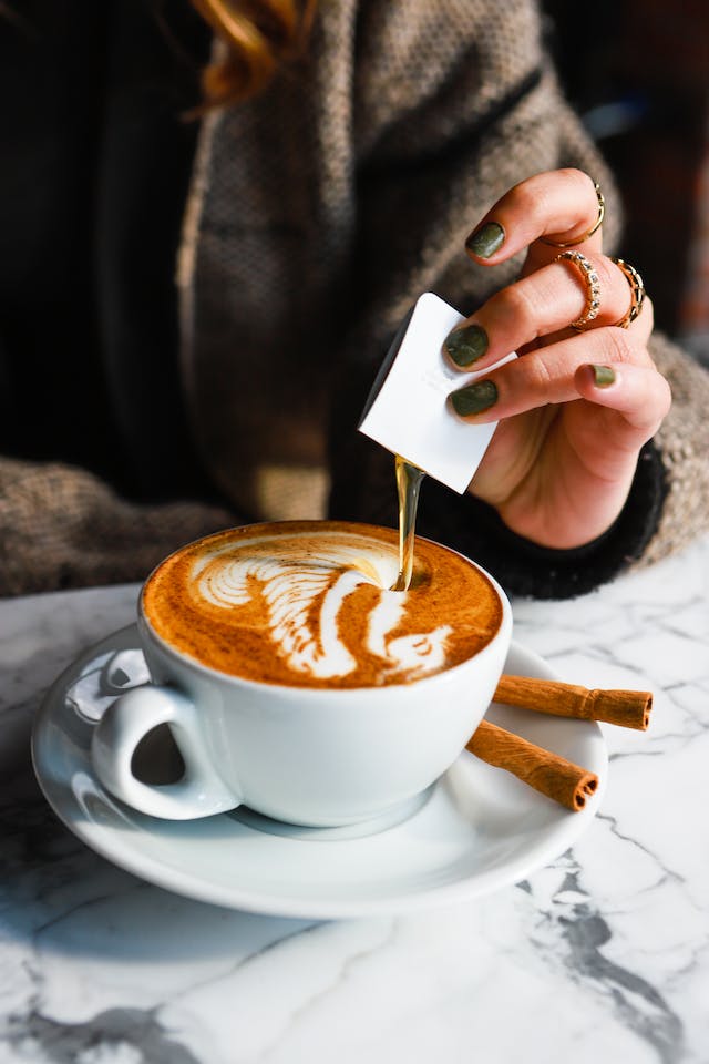 A woman pouring syrup in her hot latte.