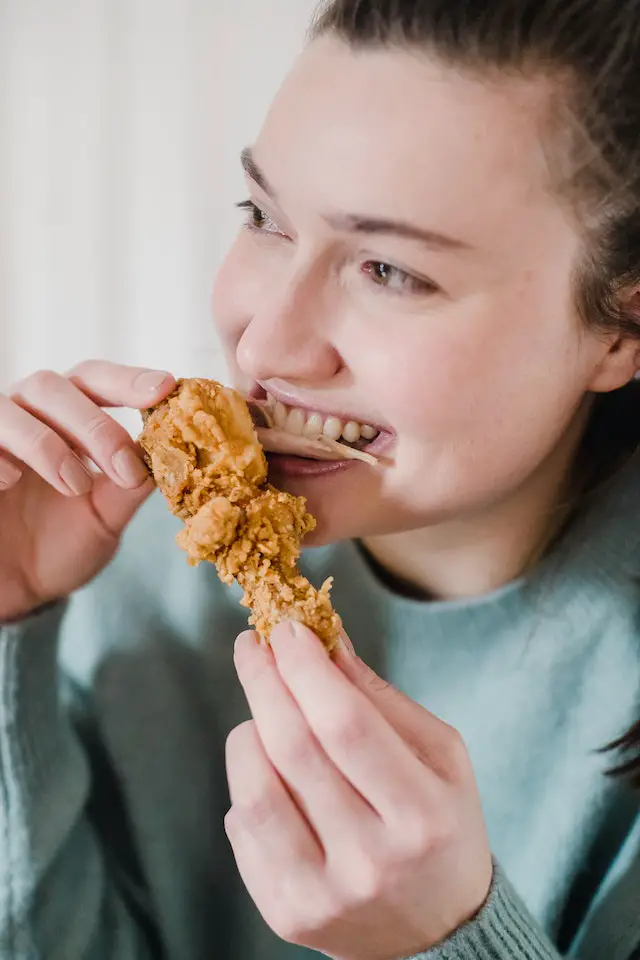 A woman eating a crunchy fried chicken