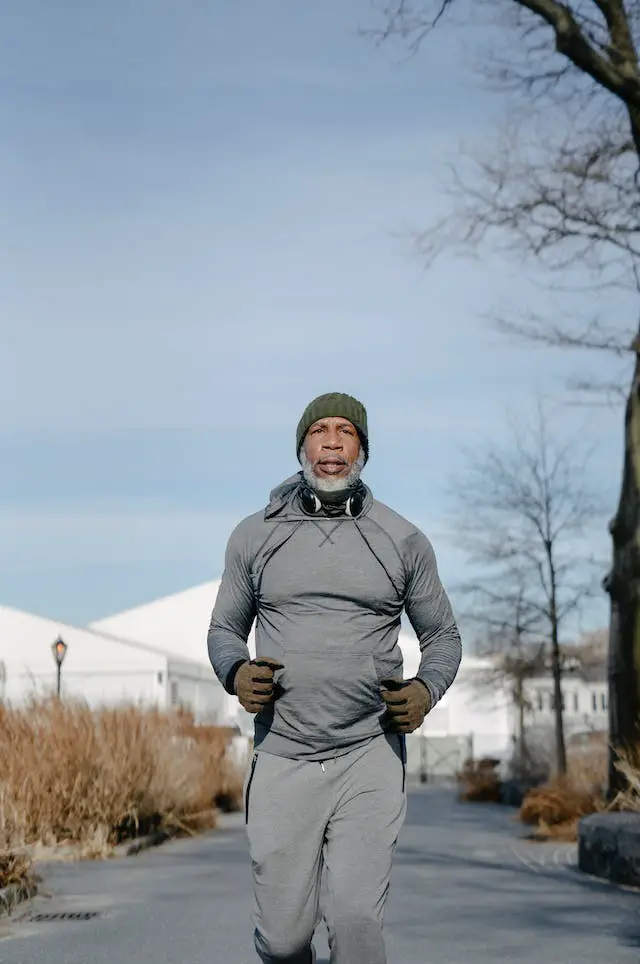 A gray-beard mature man doing a cold morning jog in the city.
