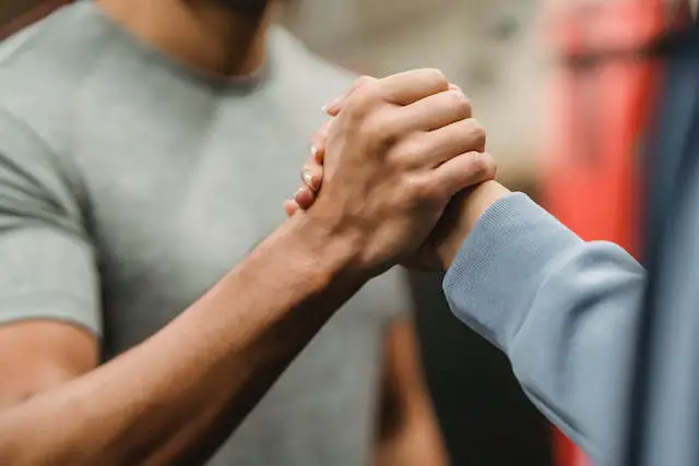 Two people clasping hands together at the gym.