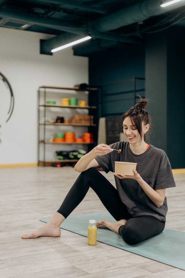 A woman eating her meal in the gym.