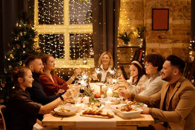 A family of seven gathered around the dining table while holding Christmas sparklers