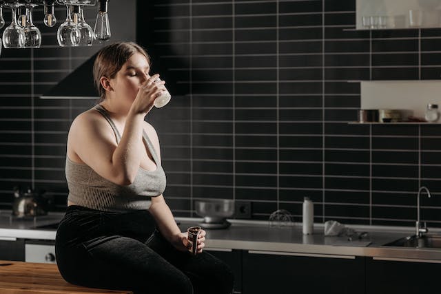 A woman sitting on the table and drinking health shake.