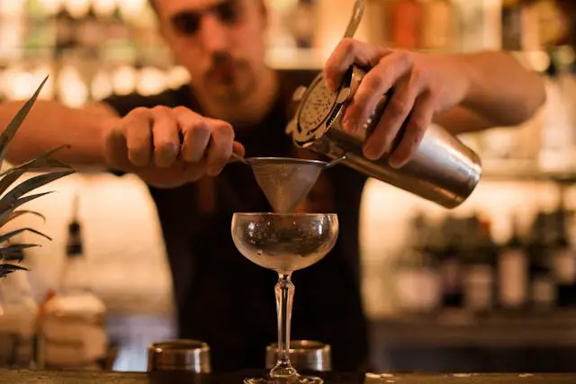 A bartender making a drink at the bar counter.