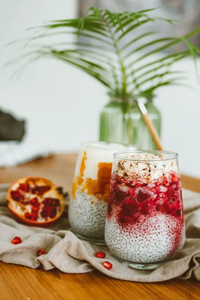 Two glasses of milky chia pudding with pomegranate.
