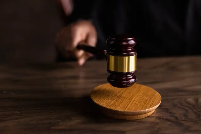 A dark brown wooden gavel on a brown wooden table.