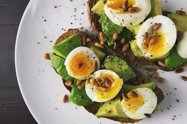 Avocado toast with poached egg sprinkled with nuts and spices.