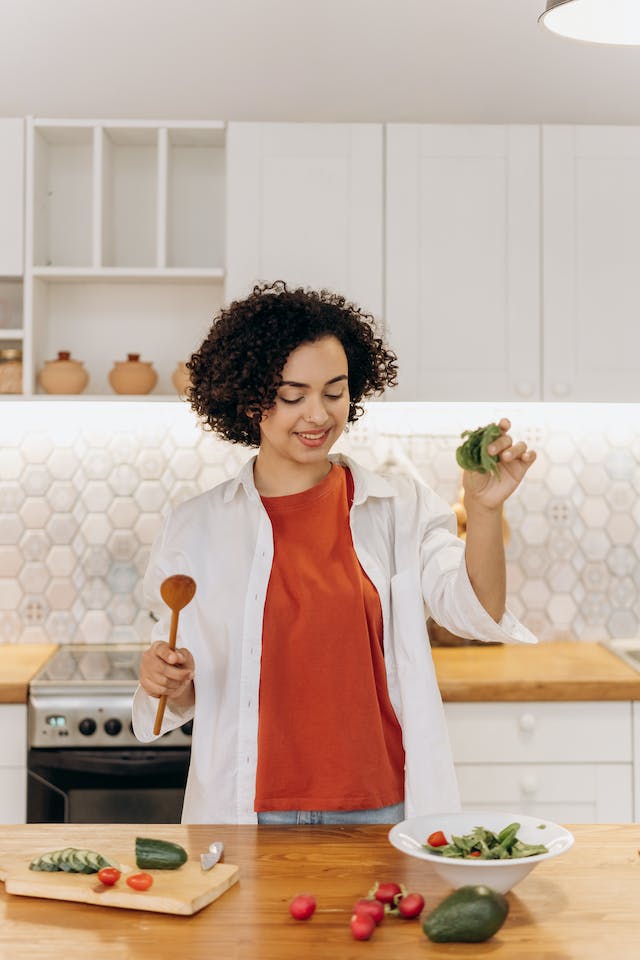 A woman making a green vegetable salad in her kitchen.