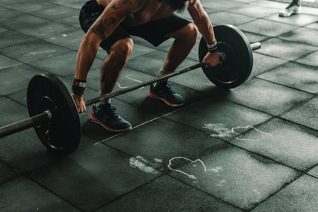 A strong-looking man trying to lift a barbell at the gym.