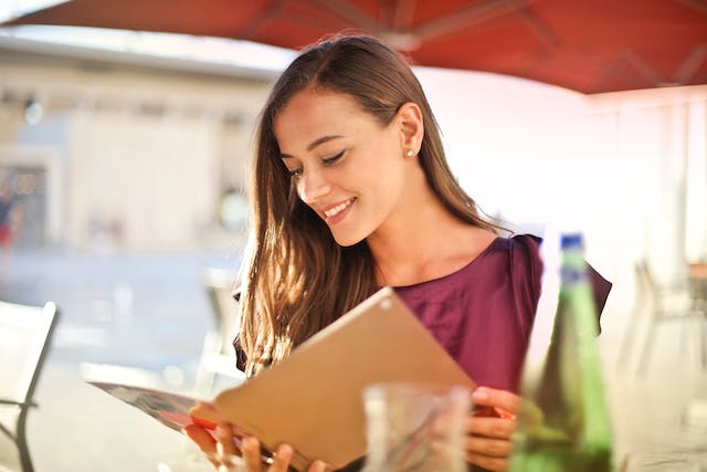 A smiling woman looking at a restaurant menu.