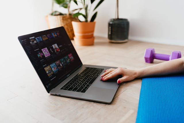 A woman's hand scrolling through her laptop while exercising.