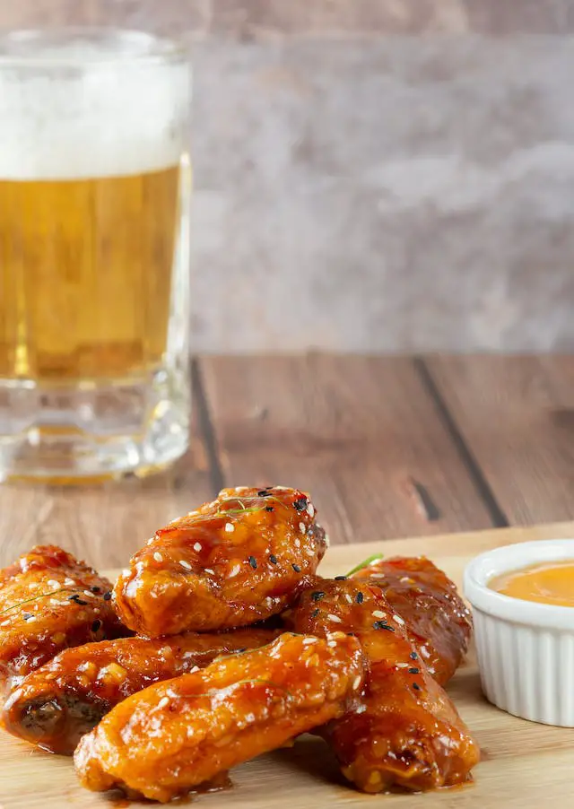 Chicken buffalo wings topped with white sesame seeds.
