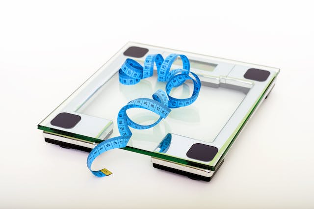 A blue measuring tape placed on top of a glass weighing scale.